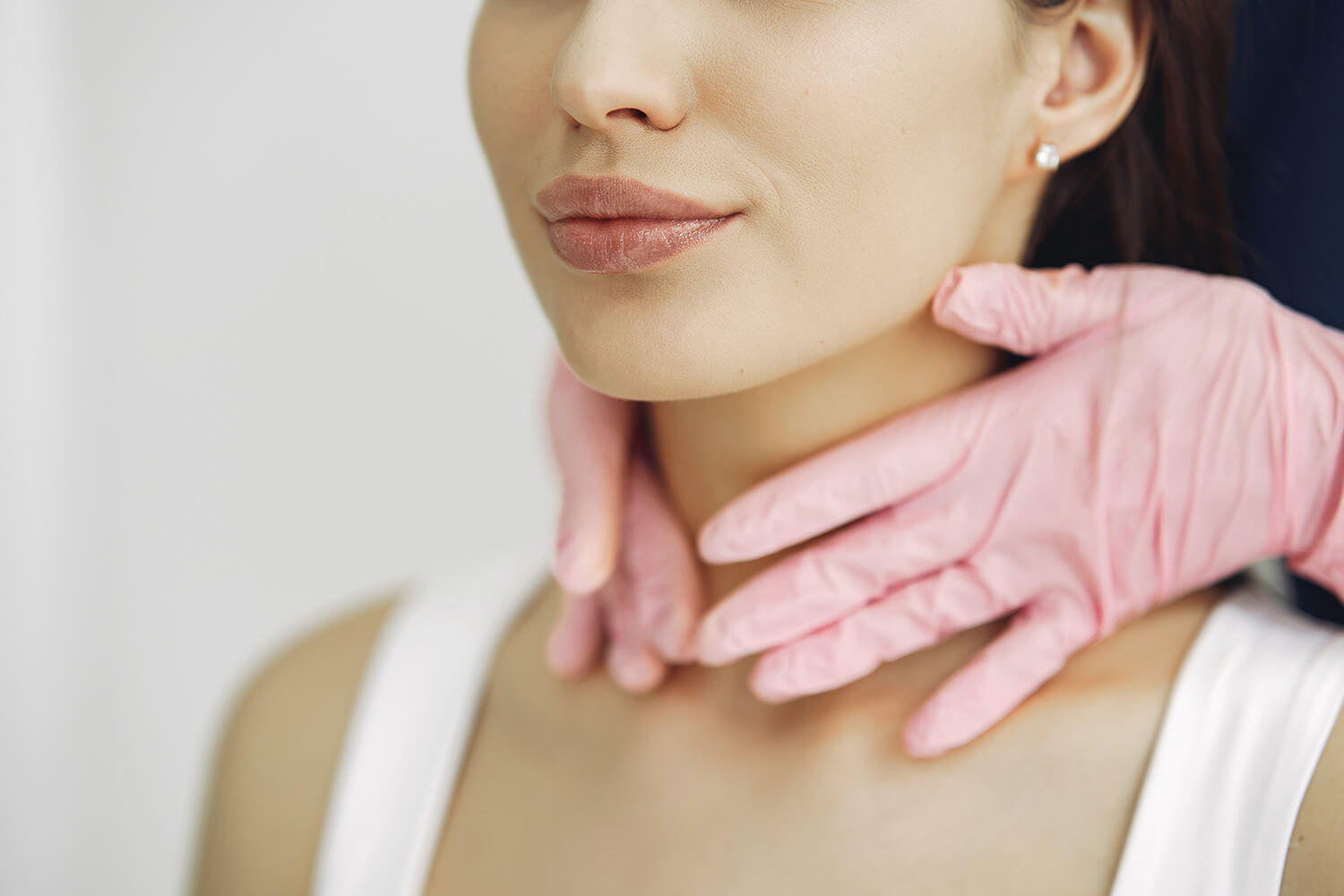 Manos con guantes rosas apoyadas en el cuello de una mujer