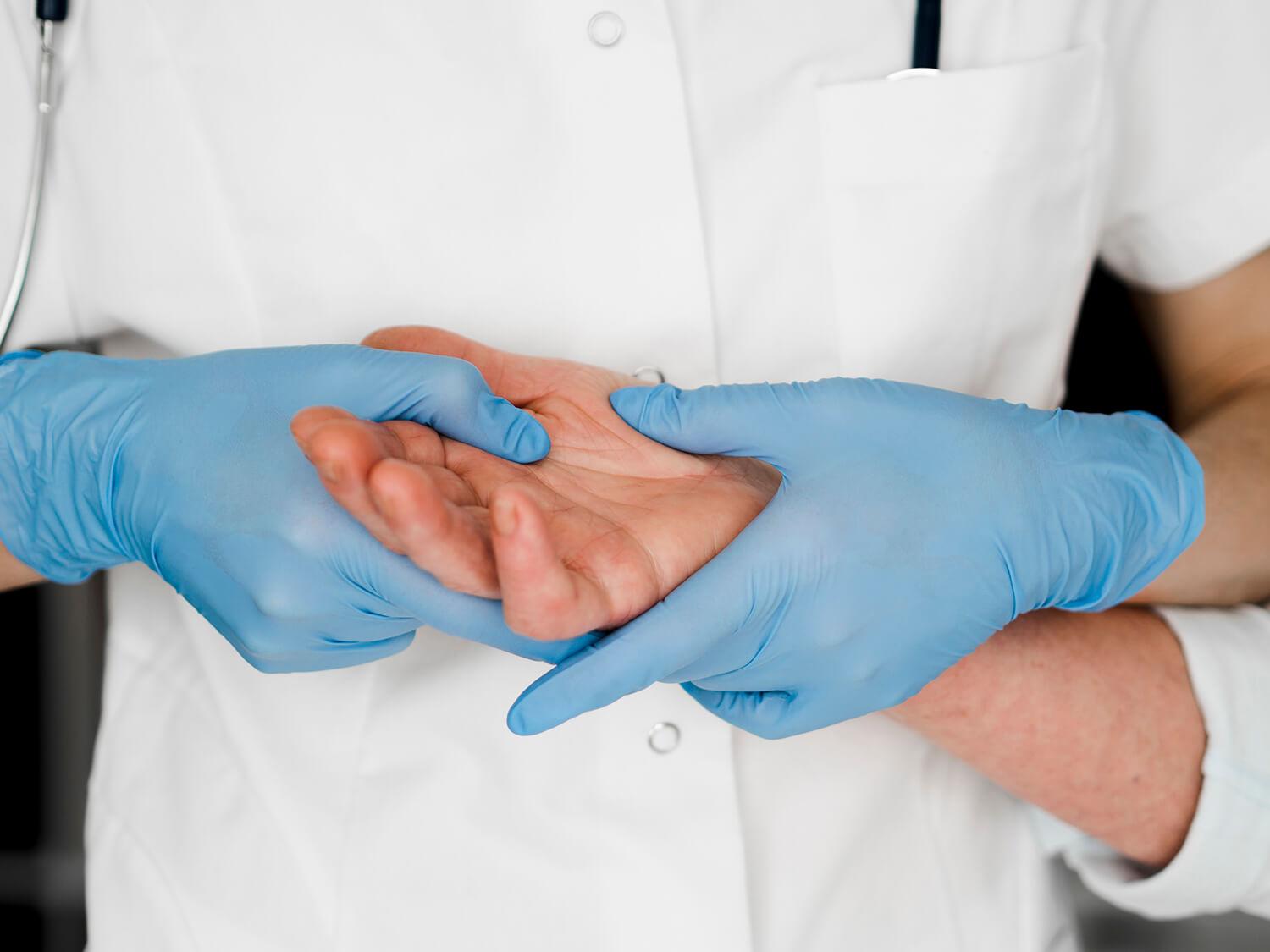 Un médico con un uniforme blanco inspecciona la mano de un señor mayor